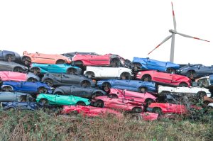 Scrap cars, scrap cars on a stack in the background a wind turbine for energy.